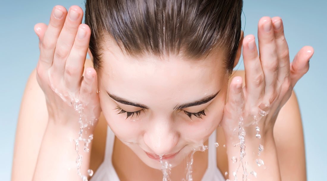 Woman washing her face with water, illustrating use of an acne control cleanser.