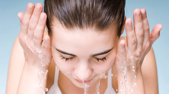 Woman washing her face with water, illustrating use of an acne control cleanser.