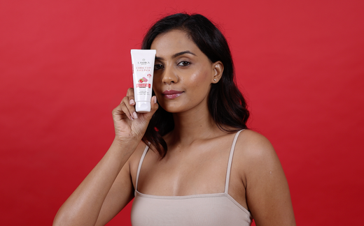 A woman displays a tube of coral clay face pack cream, highlighting its skincare benefits.