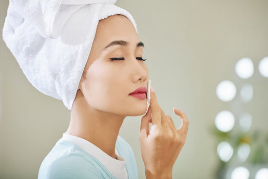 A woman applying toner on her face with cotton and feeling hydrated with that misty fresh glow