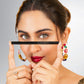 A woman displays a pair of eyeliner pencils, showcasing the black magik kajal from Lashika in her hands.
